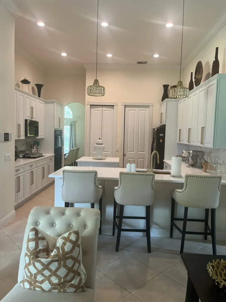 Finished kitchen with white shaker cabinets, gold hardware, stone counters, and island seating