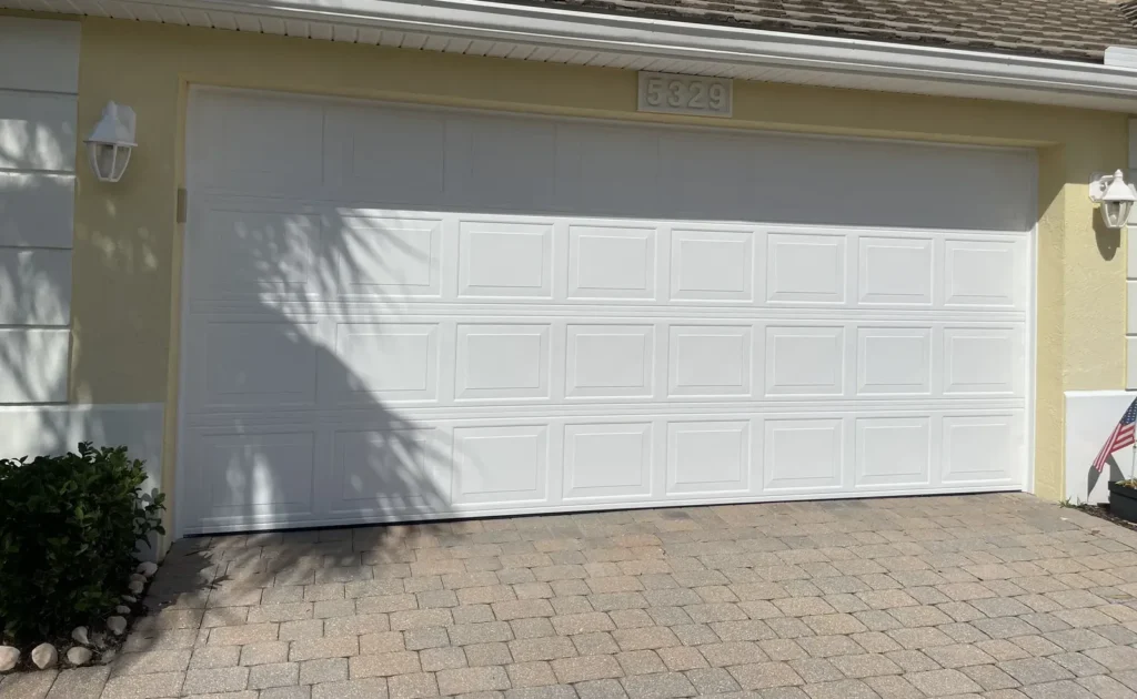 Freshly finished white paneled garage door on a home exterior
