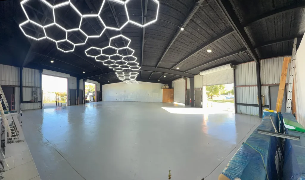 Large commercial interior with honeycomb LED ceiling lights and a glossy epoxy floor