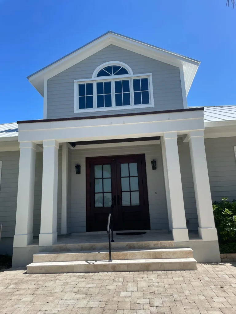 Finished home front entrance with dark double doors, white columns, and a covered porch