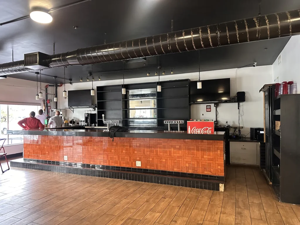 Finished commercial bar with orange tile front, dark countertop, and pendant lights